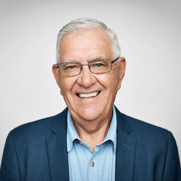 Homem idoso sorrindo, de óculos e blazer azul